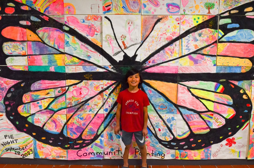 Student in front of giant butterfly wings.